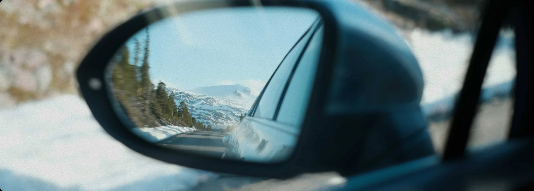 Snowy road reflected in a car wing mirror