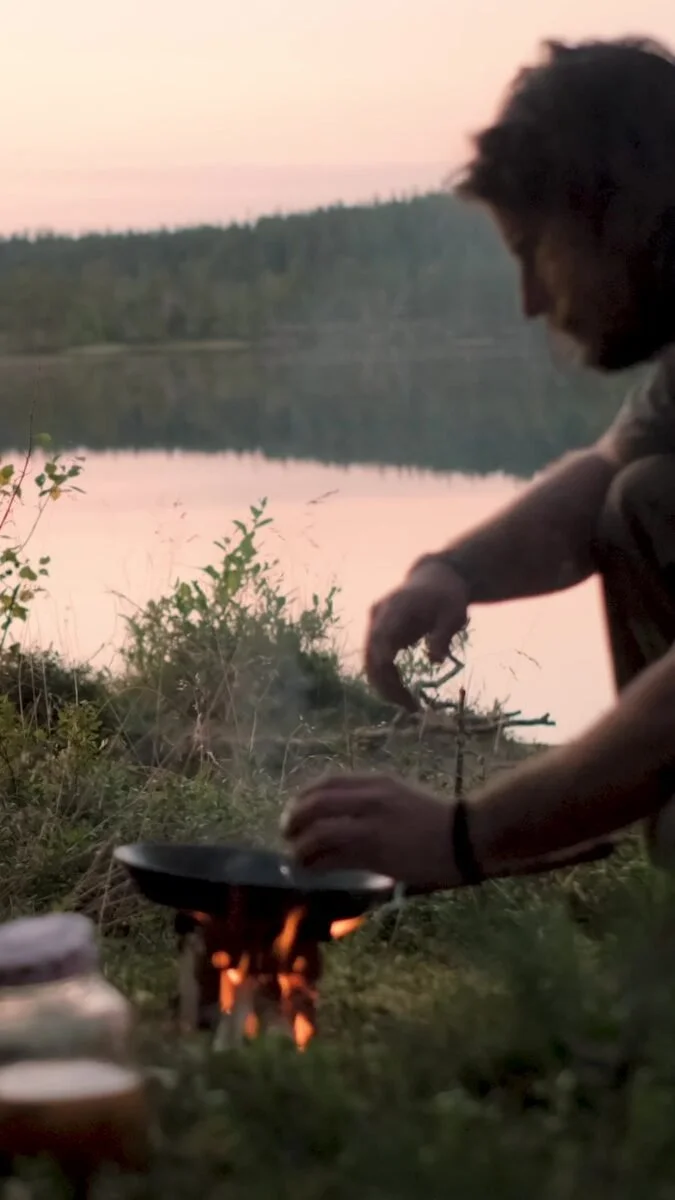 Cooking over a small fire by the lake at dusk