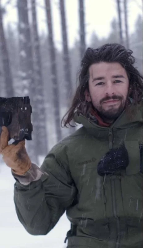 George holding a hand-forged blade in the snow