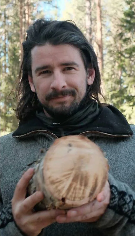 George holding a log slice in the forest