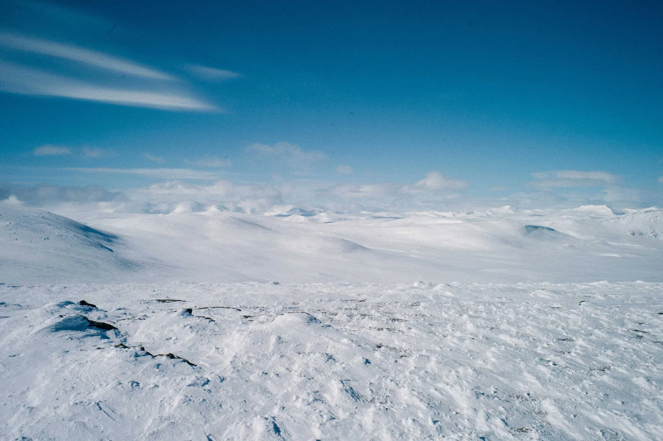 Wind-swept snow plateau under a deep blue sky