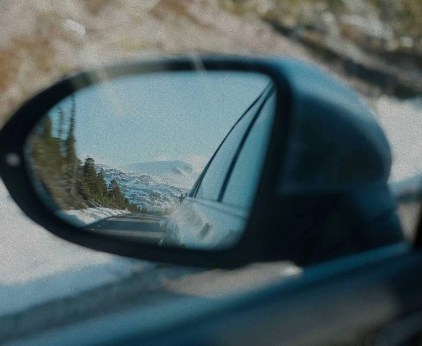 Snowy road reflected in a car wing mirror