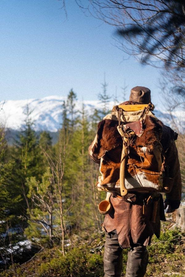 Man with a fur pack walking toward snowy mountains