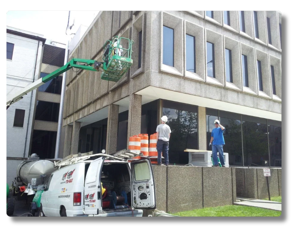 Hot Shot Pressure Washing crew cleaning multi-story office building windows in Roanoke VA with boom lift access