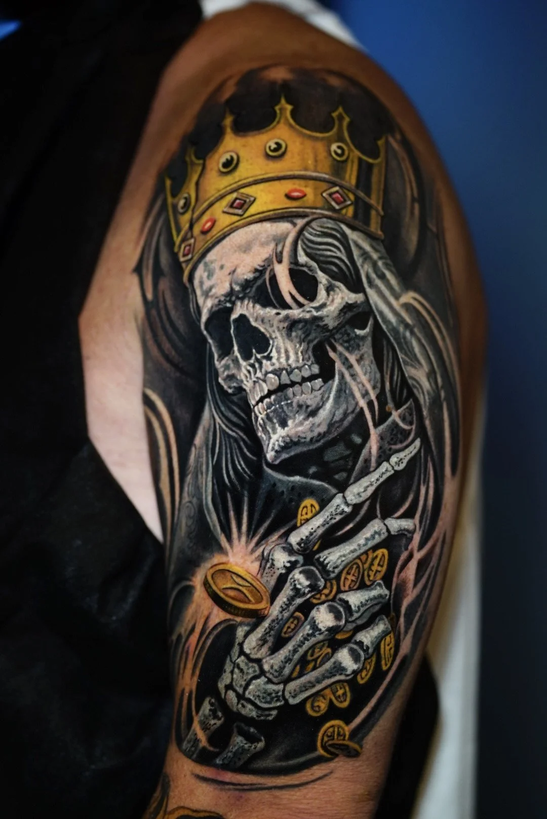 Color crowned skeleton and glowing ring upper-arm tattoo at Black Craft Tattoo Collective in Charlotte, NC.