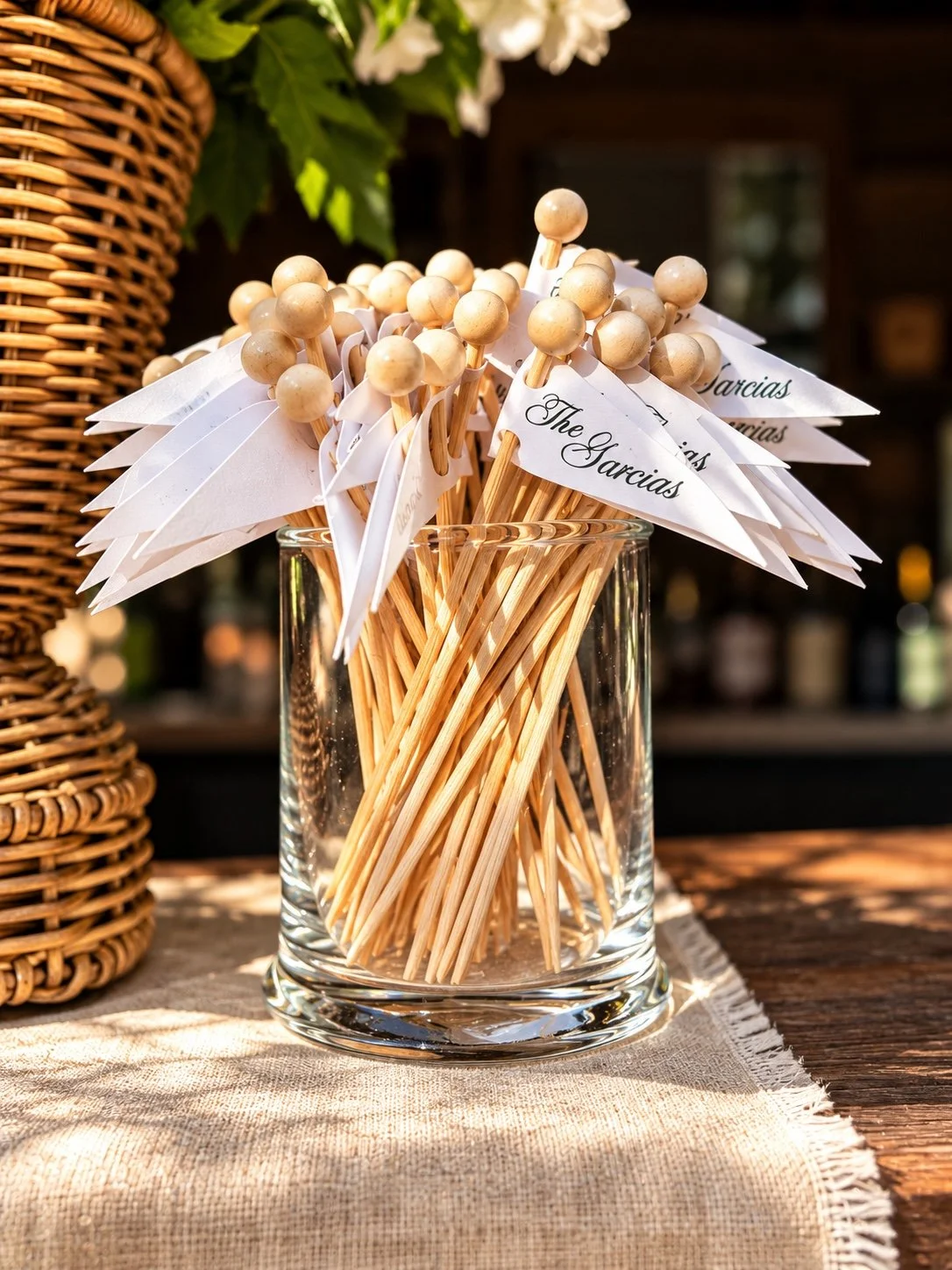 Personalized wedding drink flags arranged in a glass beside white flowers