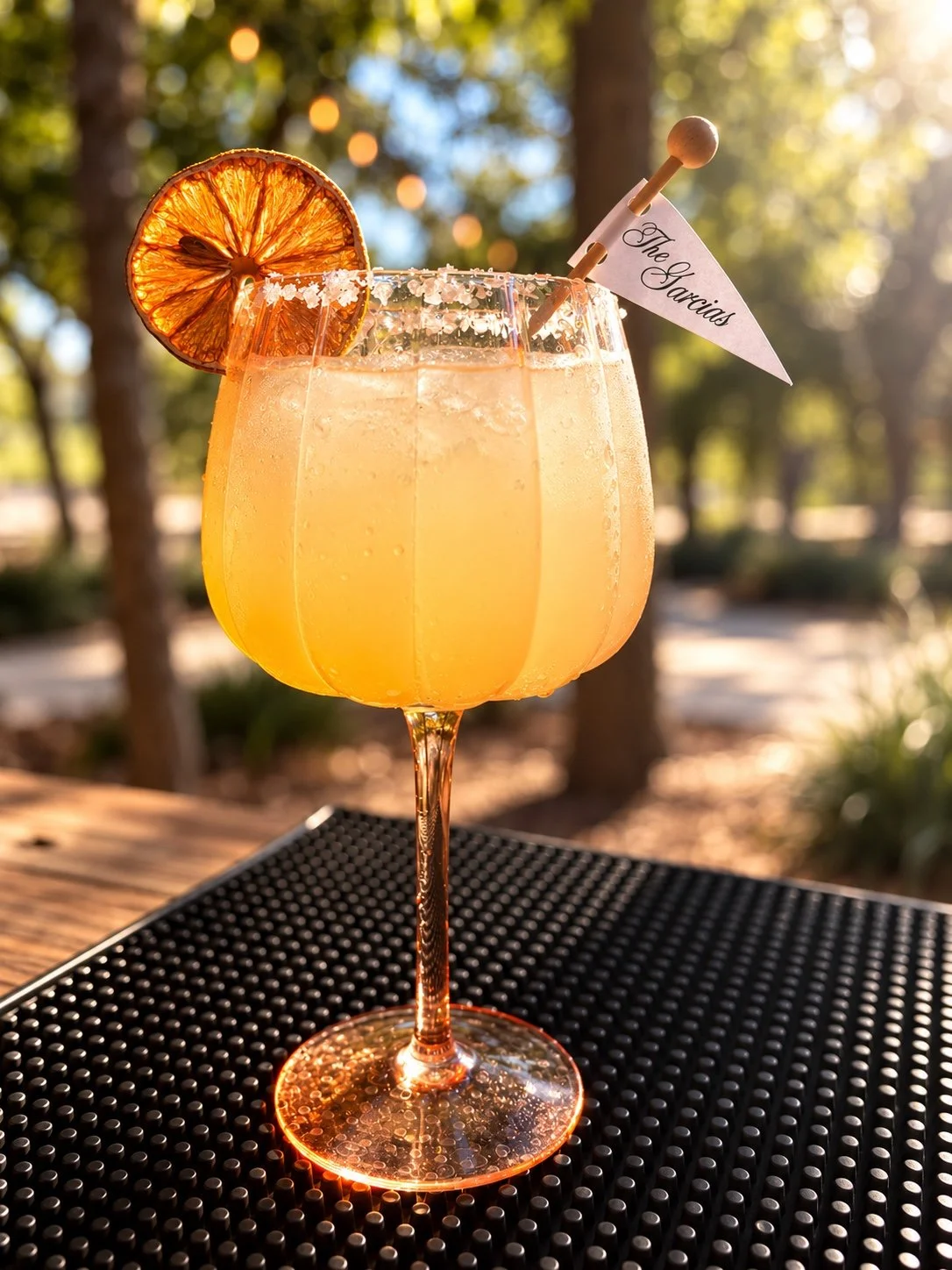 Orange wedding cocktail with a dried citrus garnish and personalized drink flag at an Ellie Bar Co. bar