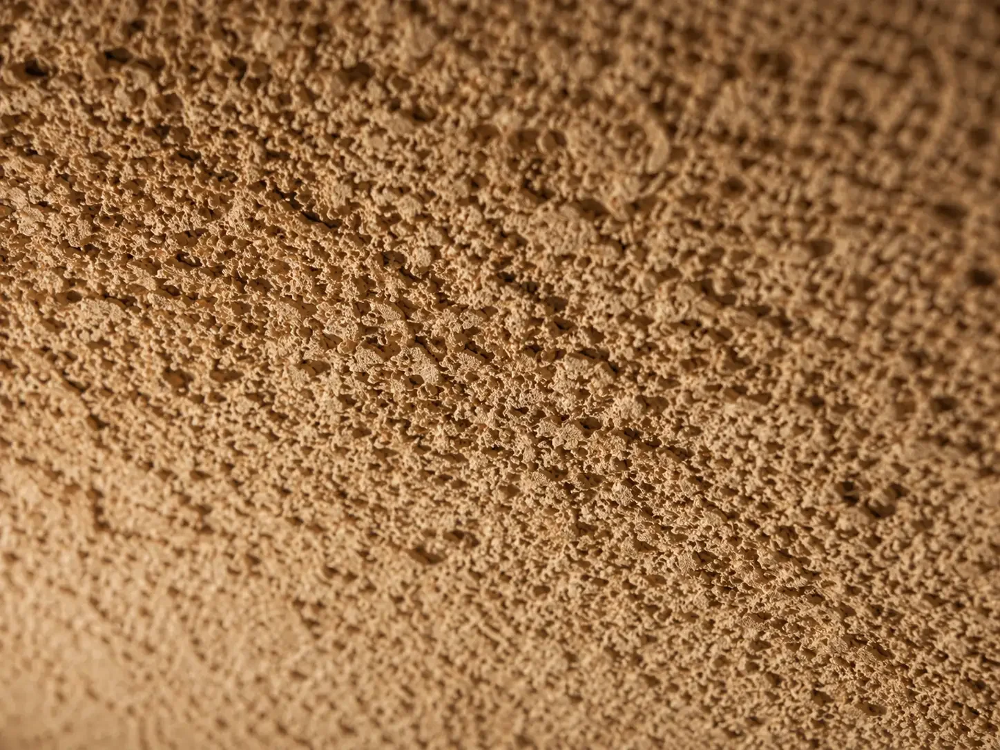 Detail van gespoten kurklaag op plafond, textuur zichtbaar
