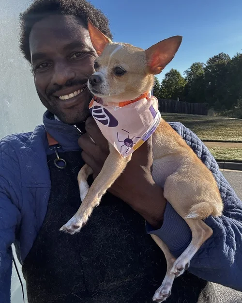 A Chihuahua held by our Lead Groomer in morning sun