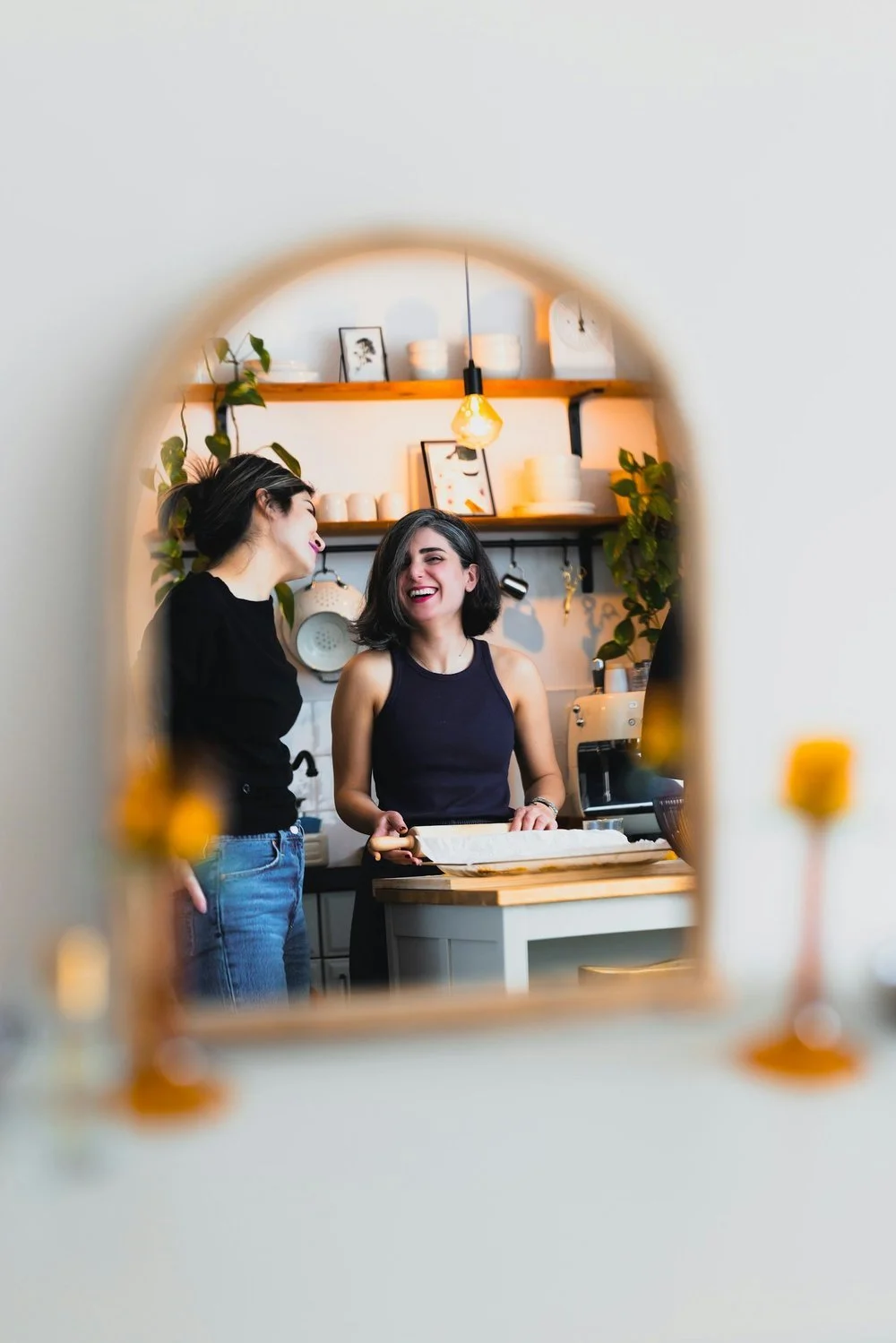 Two friends laughing in a cozy kitchen.