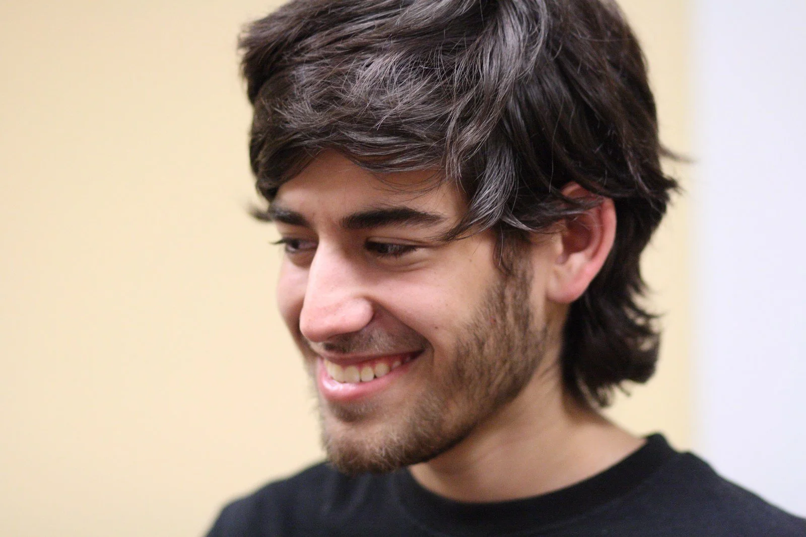 Aaron Swartz smiling and looking downward, wearing a dark shirt.