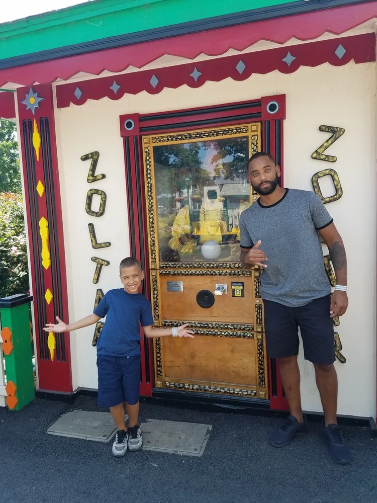 Rashad and his son beside an arcade fortune-telling machine.