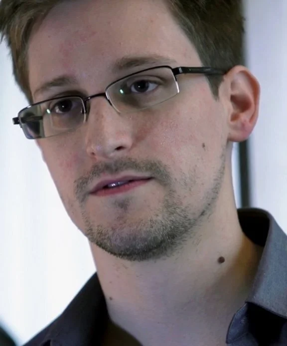 Close-up of Edward Snowden wearing glasses during an interview.