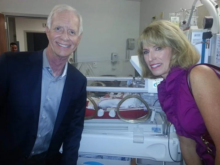 Two relatives visiting a newborn in the hospital.