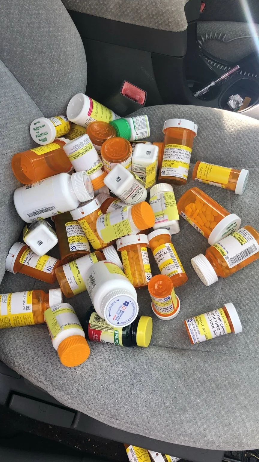 Prescription and supplement bottles gathered on a car seat.
