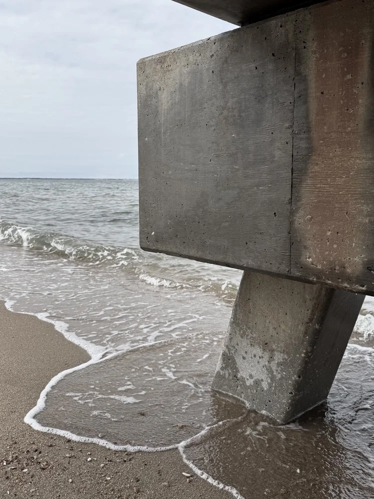 A concrete pier support meeting the sea.