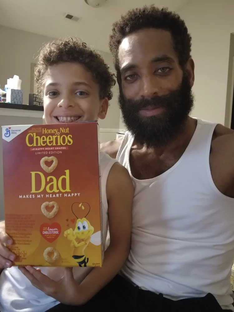 Rashad and his son holding a Dad cereal box.