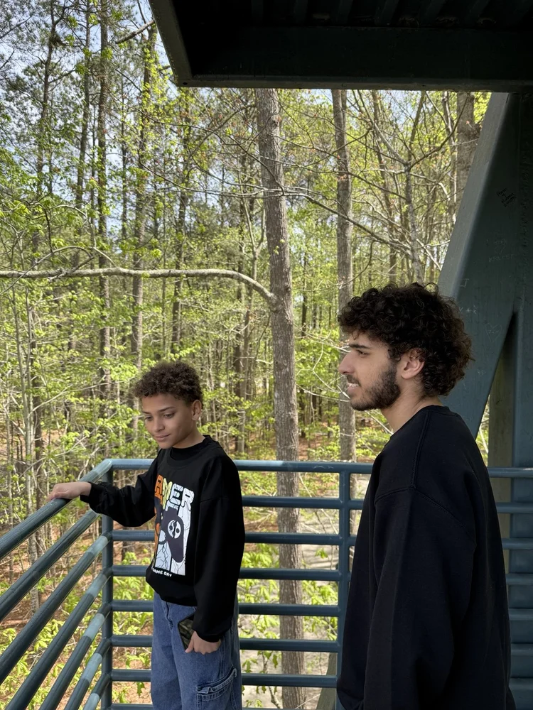 Two brothers looking out toward the trees.
