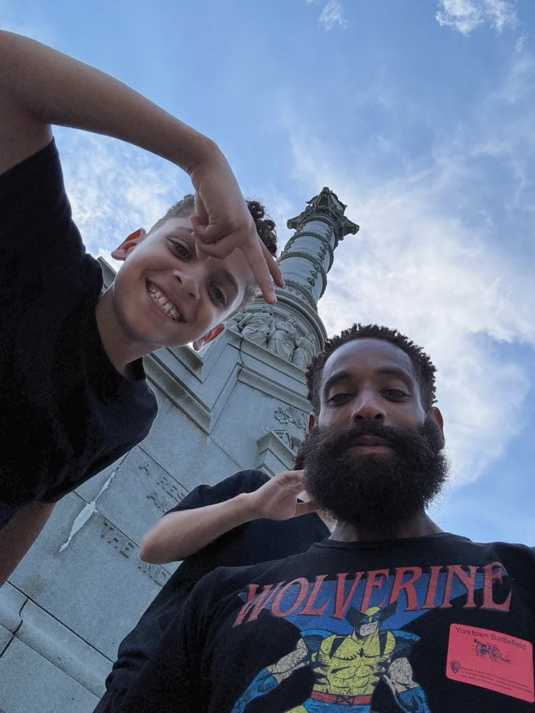Rashad and his sons beneath a monument at Yorktown
