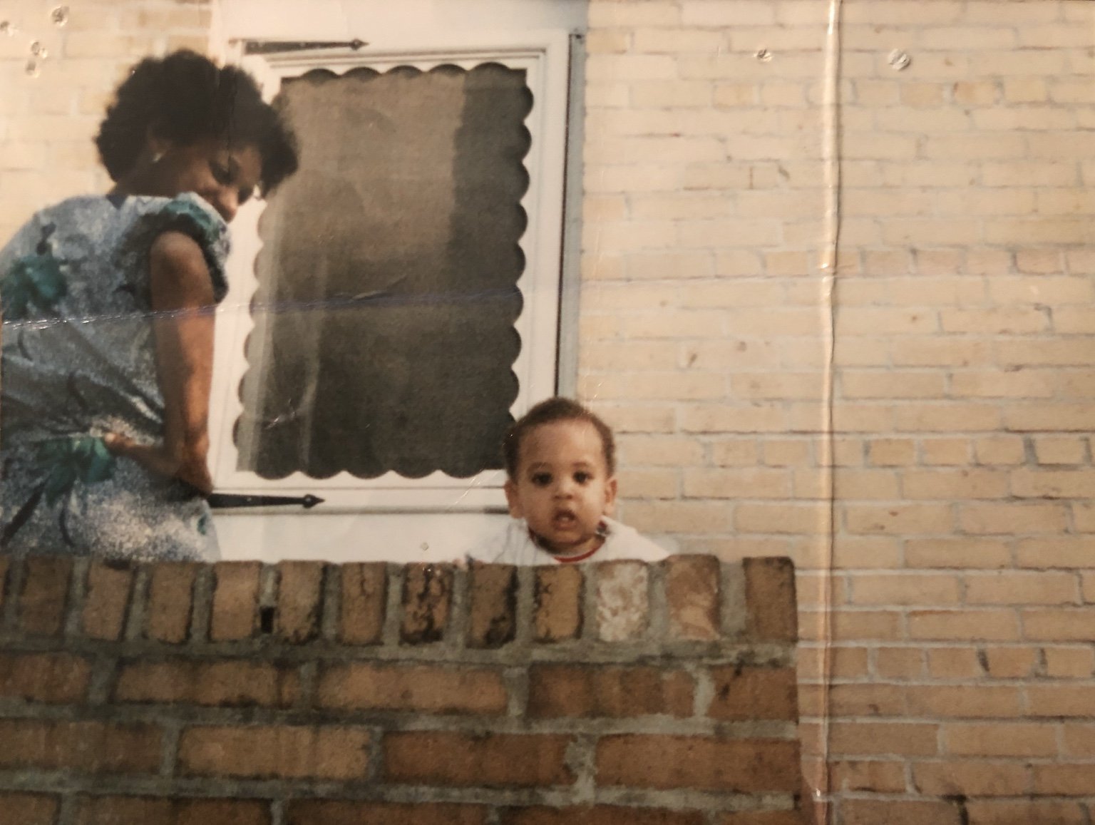 A childhood family photograph beside a brick wall.