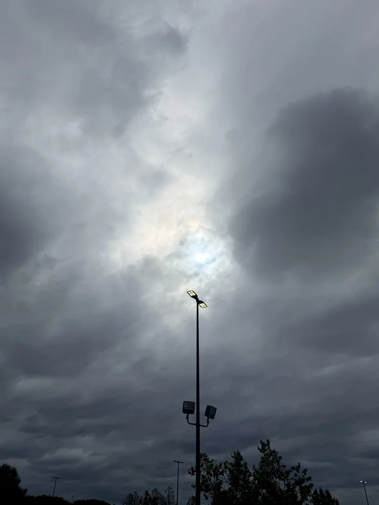 A tall light pole beneath storm clouds.