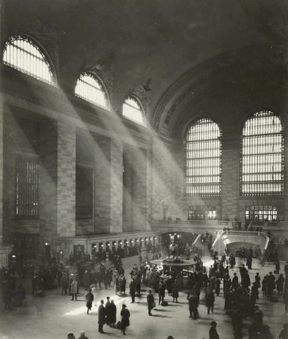Sunbeams cross the vast Main Concourse above travelers in a historic black-and-white photograph.
