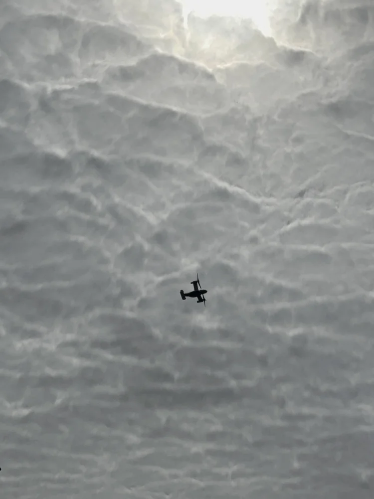 An aircraft silhouetted against textured clouds.