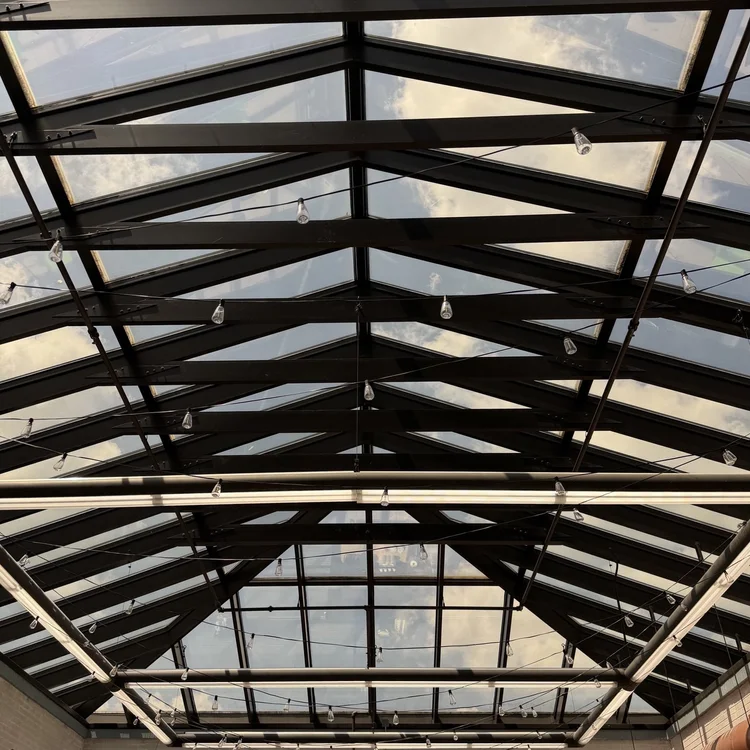 Steel roof beams forming a geometric pattern overhead.