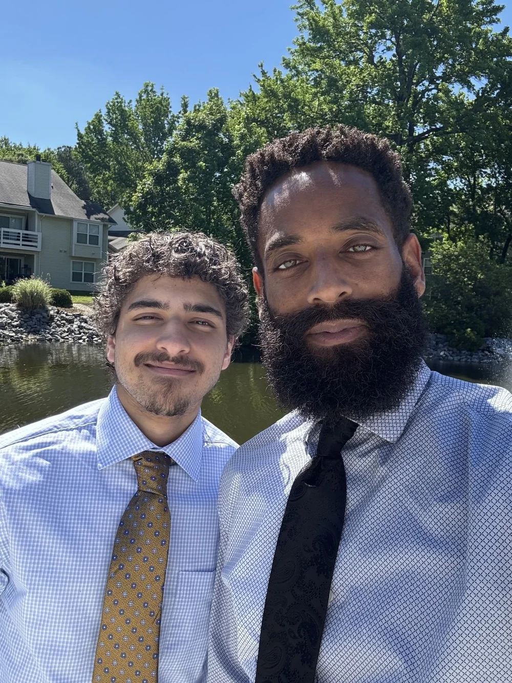 Rashad and his son wearing shirts and ties beside the water.
