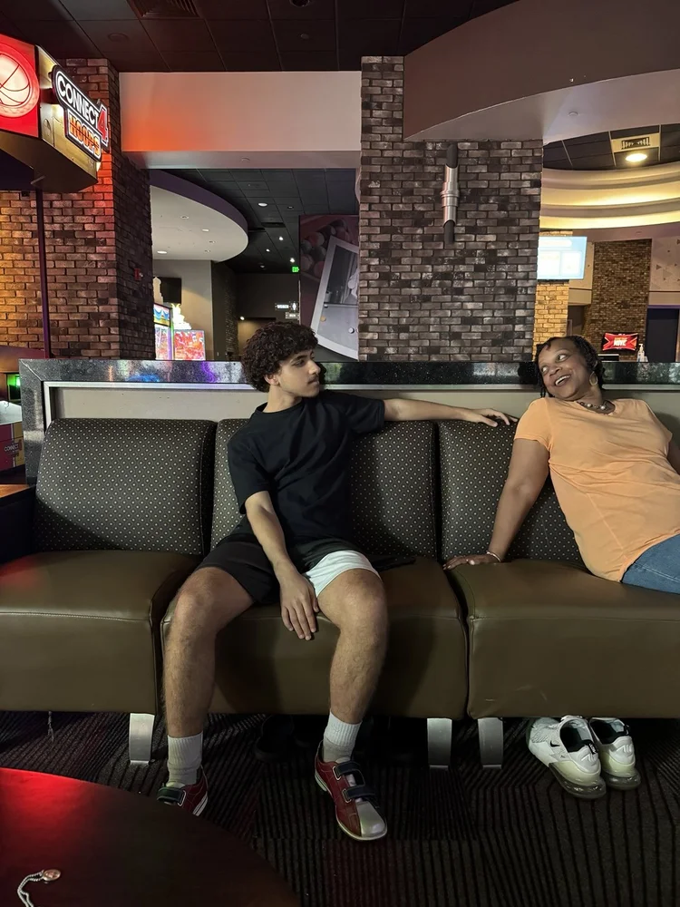 Omari and his grandmother seated beside each other in a restaurant booth.