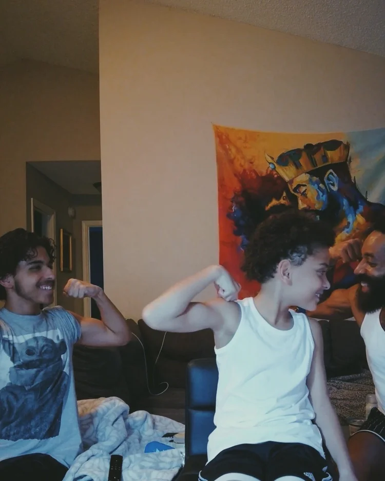 Rashad and his sons flexing their arms together at home.