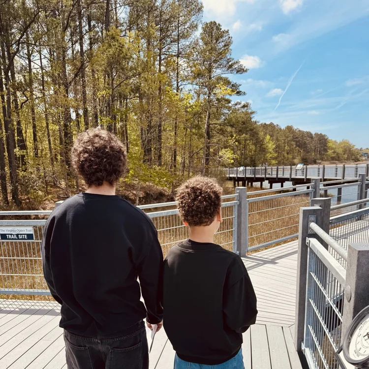 Two brothers standing side by side, facing the water.
