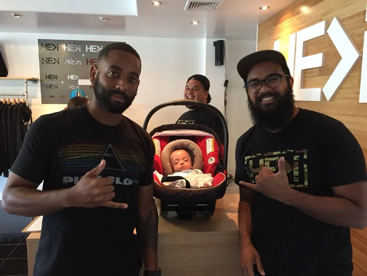 Rashad and another man beside a baby in a carrier.