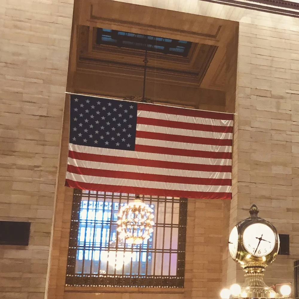 An American flag and illuminated clock inside Grand Central Terminal.