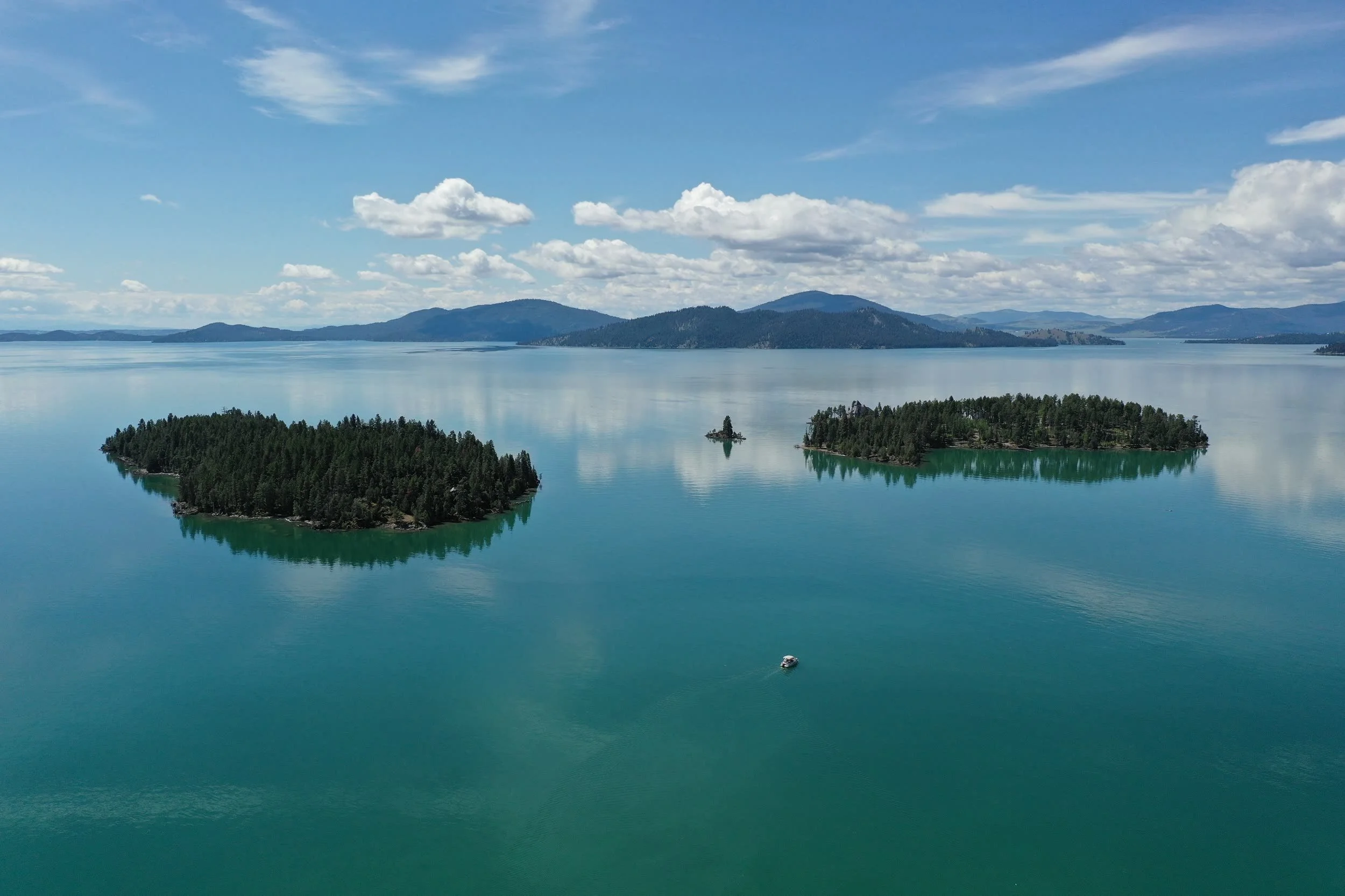 Aerial view of Flathead Lake's turquoise water and Wild Horse Island with the Mission Mountains beyond — five minutes from North Shore Landing in Somers, Montana