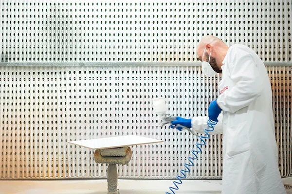 Verinlegno technician spray-applying a coating to a test panel in an application booth