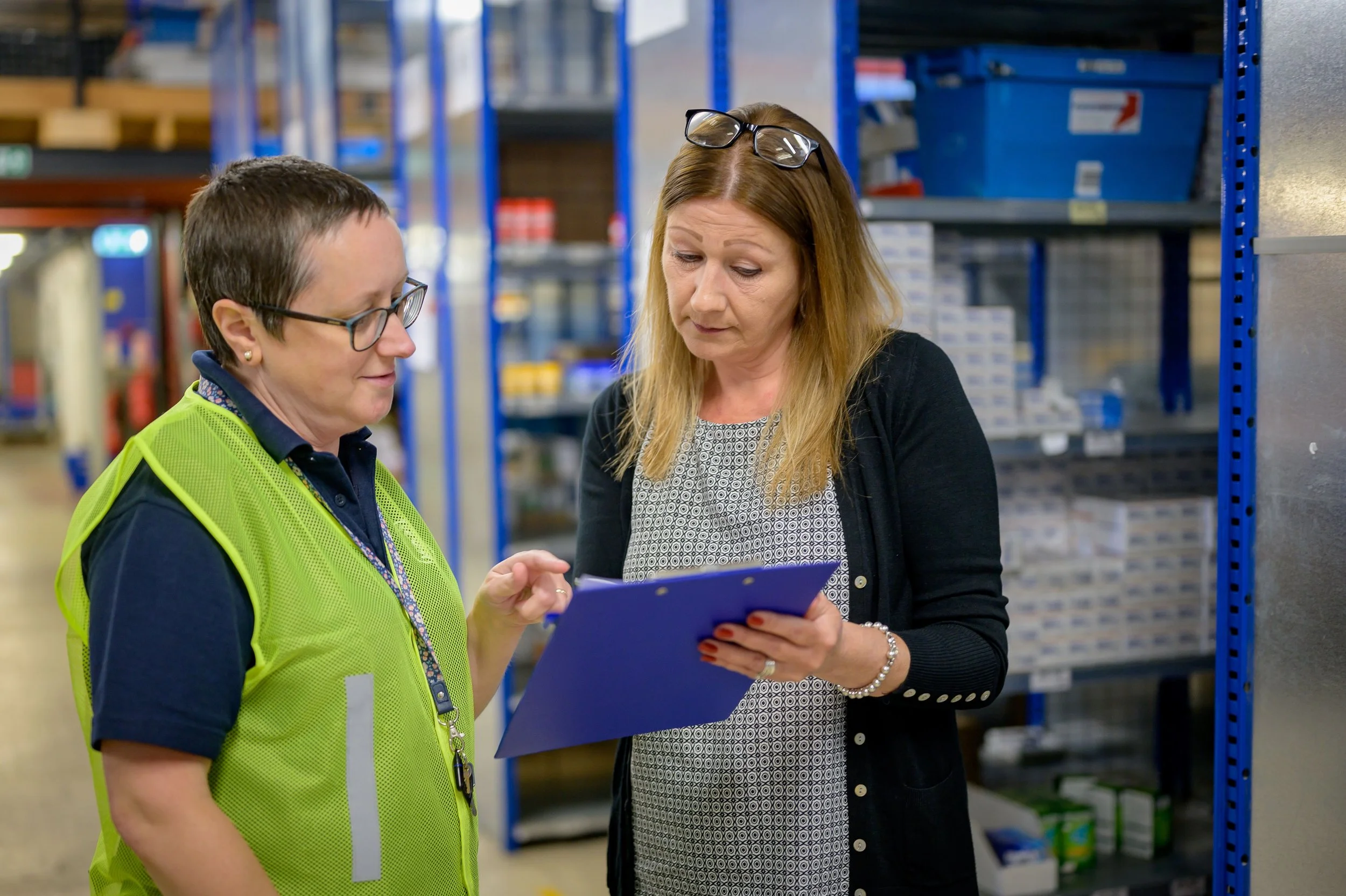 Two warehouse employees talking on the floor