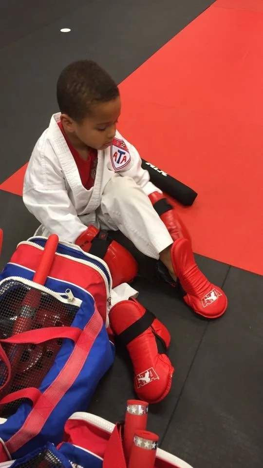 Original phone snap: phone snap of a boy sitting on the mats in his karate gear