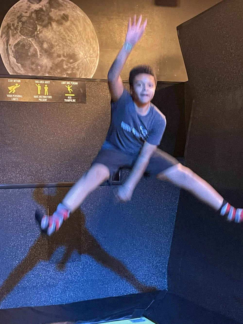 Original phone snap: blurry phone snap of a teen mid-jump at a trampoline park