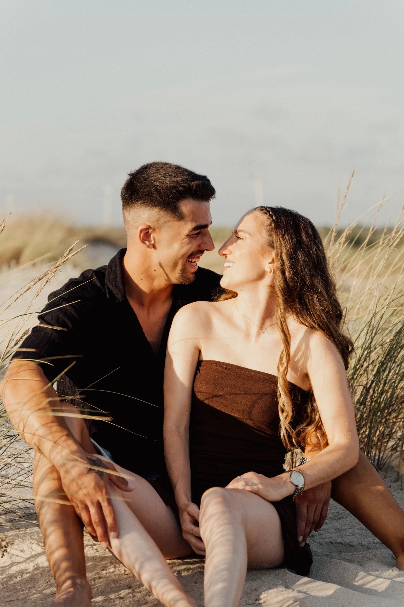 Casal sentado nas dunas ao fim da tarde
