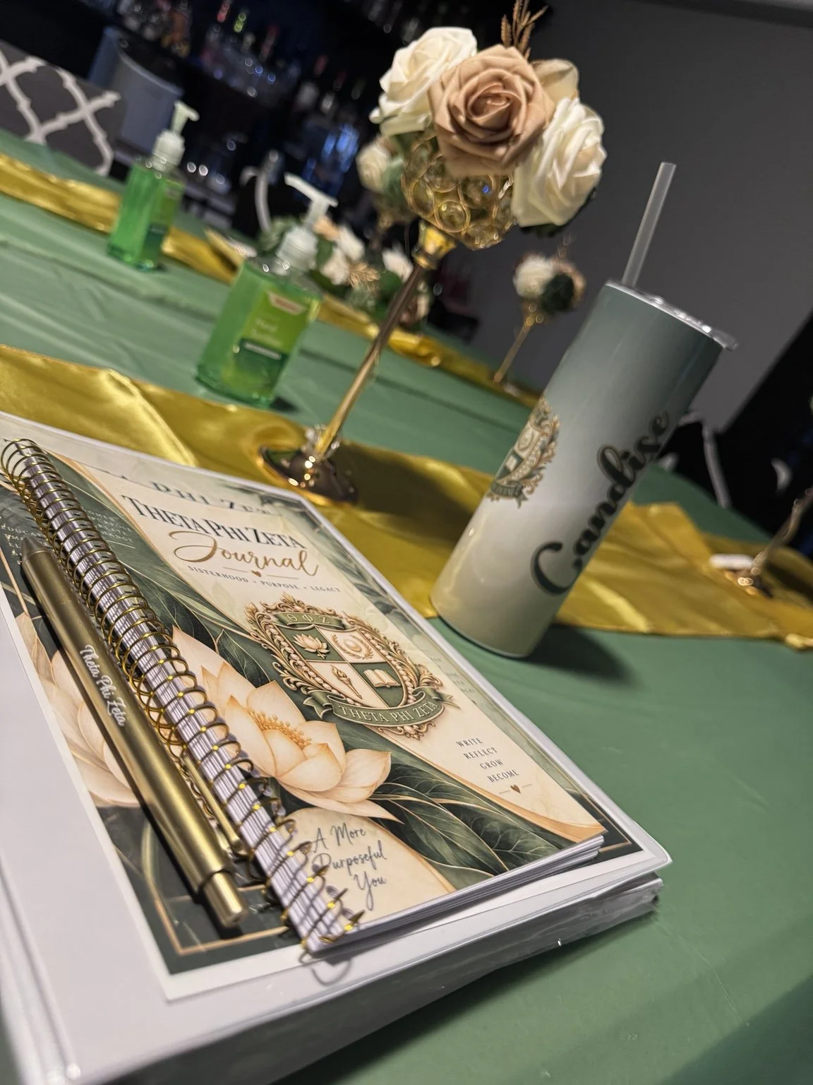 Theta Phi Zeta journal and tumbler with flowers on the table