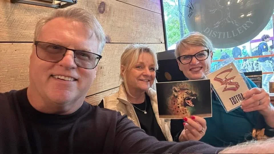 Kelly Lynne Figueiredo with two supporters holding Unannounced Authority materials during ArtPrize 2026.