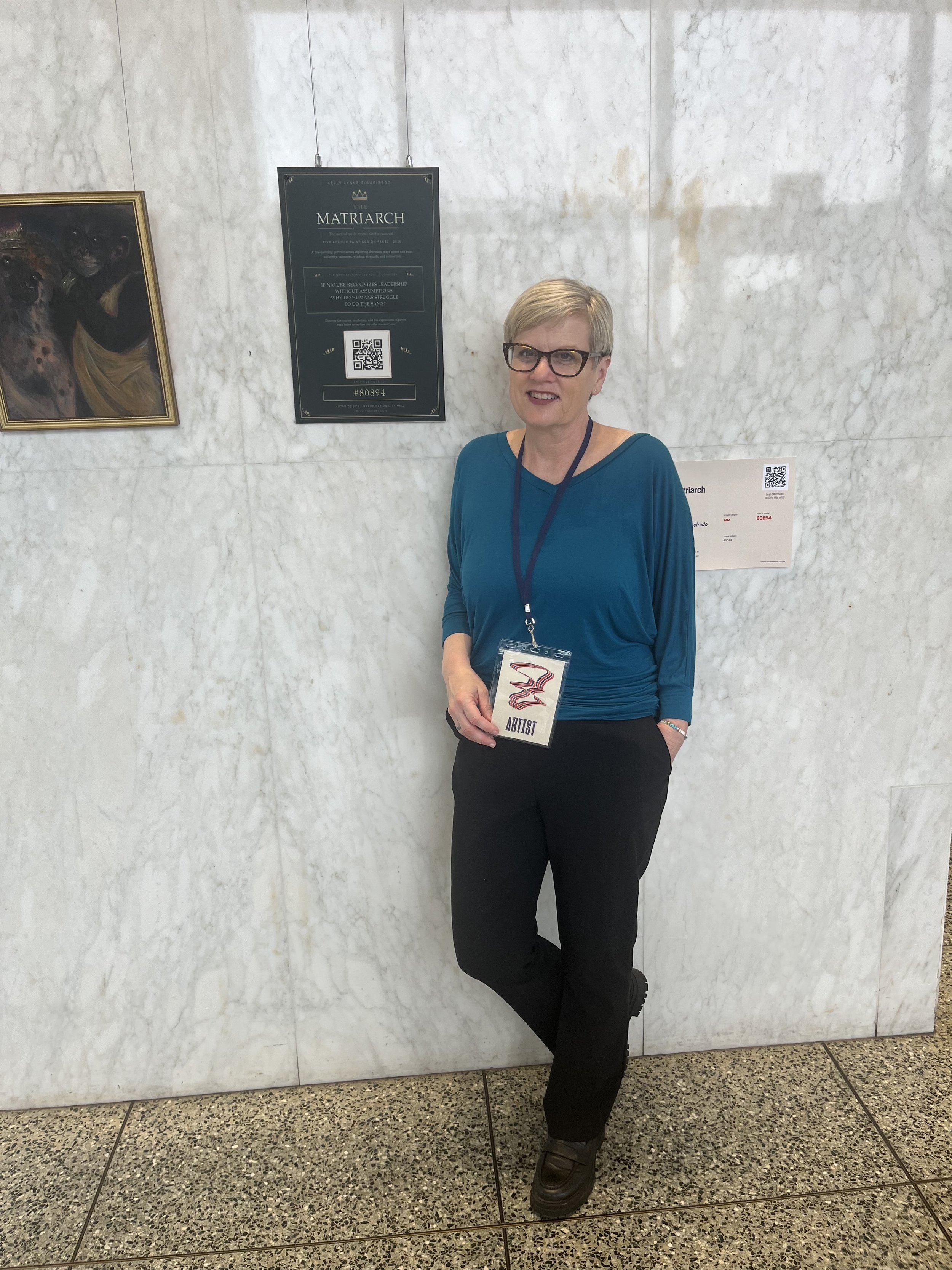 Kelly Lynne Figueiredo beside The Matriarch exhibition signage at Grand Rapids City Hall.