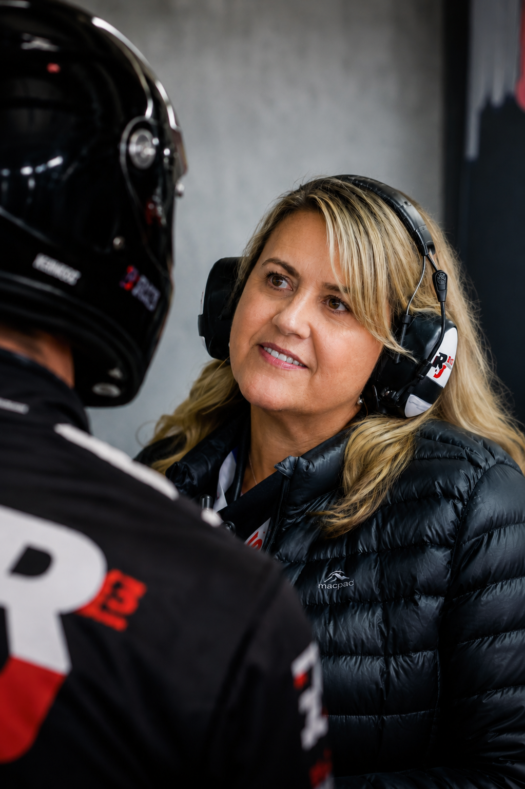 Adele White speaking with a driver in elite motorsport