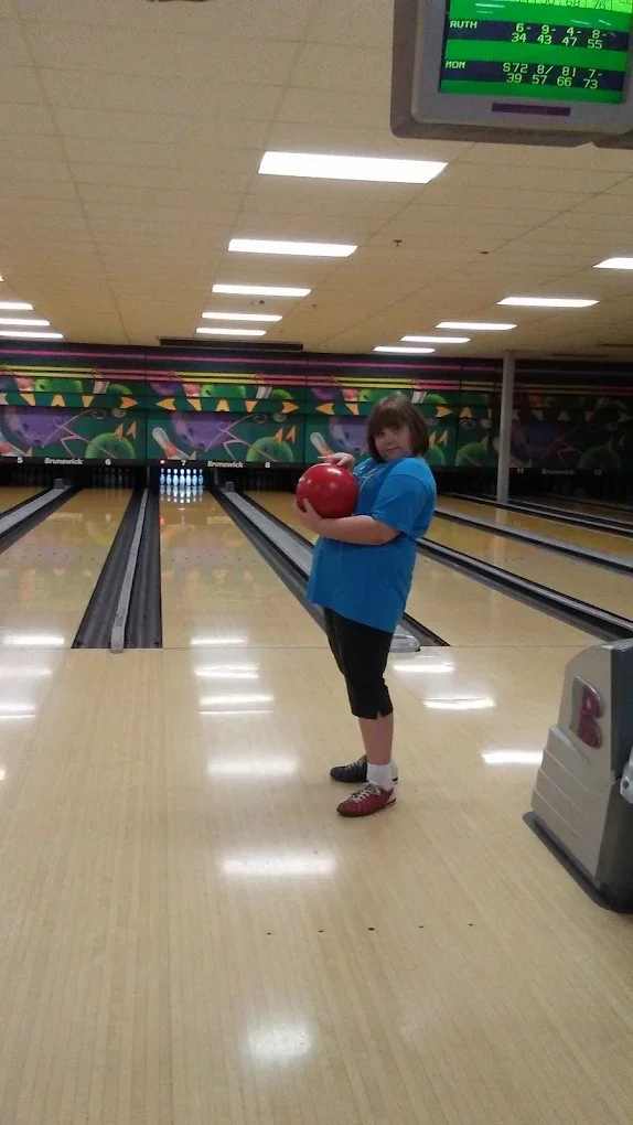A child holding a bowling ball on the lanes at Strikers