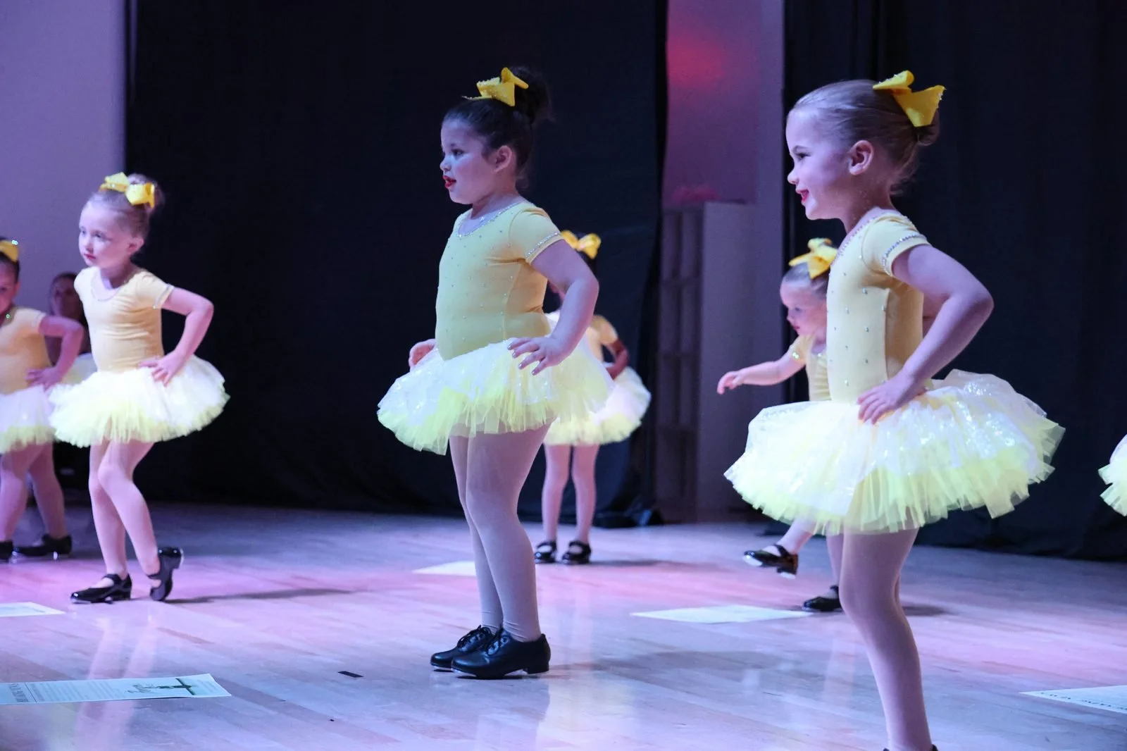Young tap dancers in yellow tutus performing at the recital