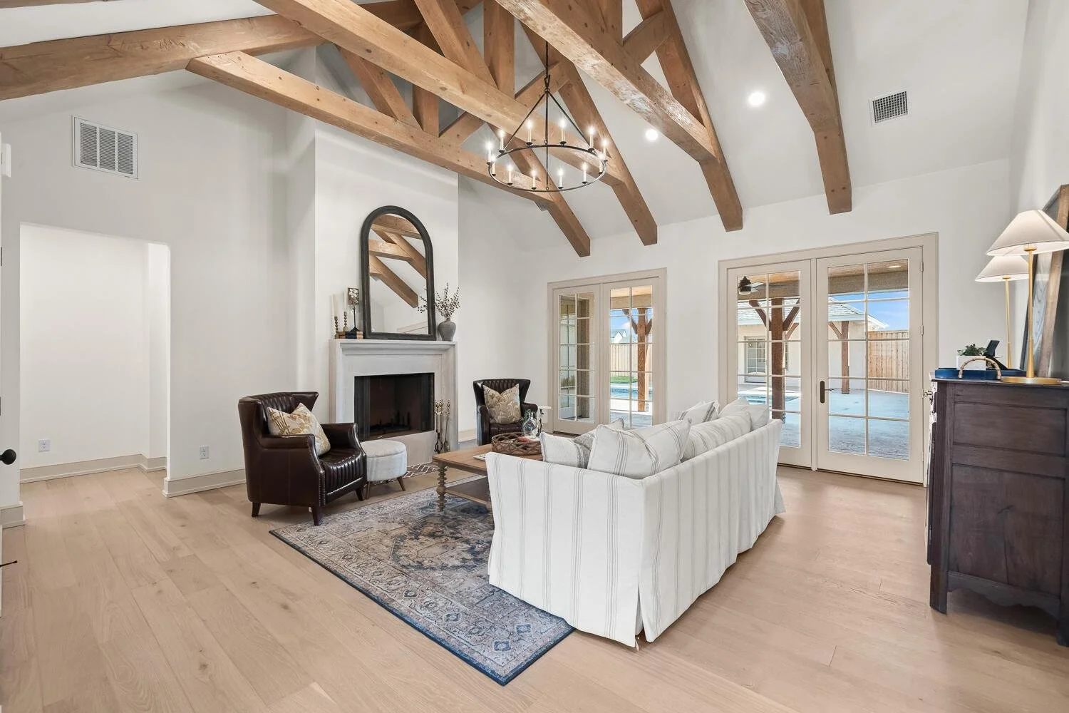 Living room with exposed wood beams, a fireplace, and glass patio doors.