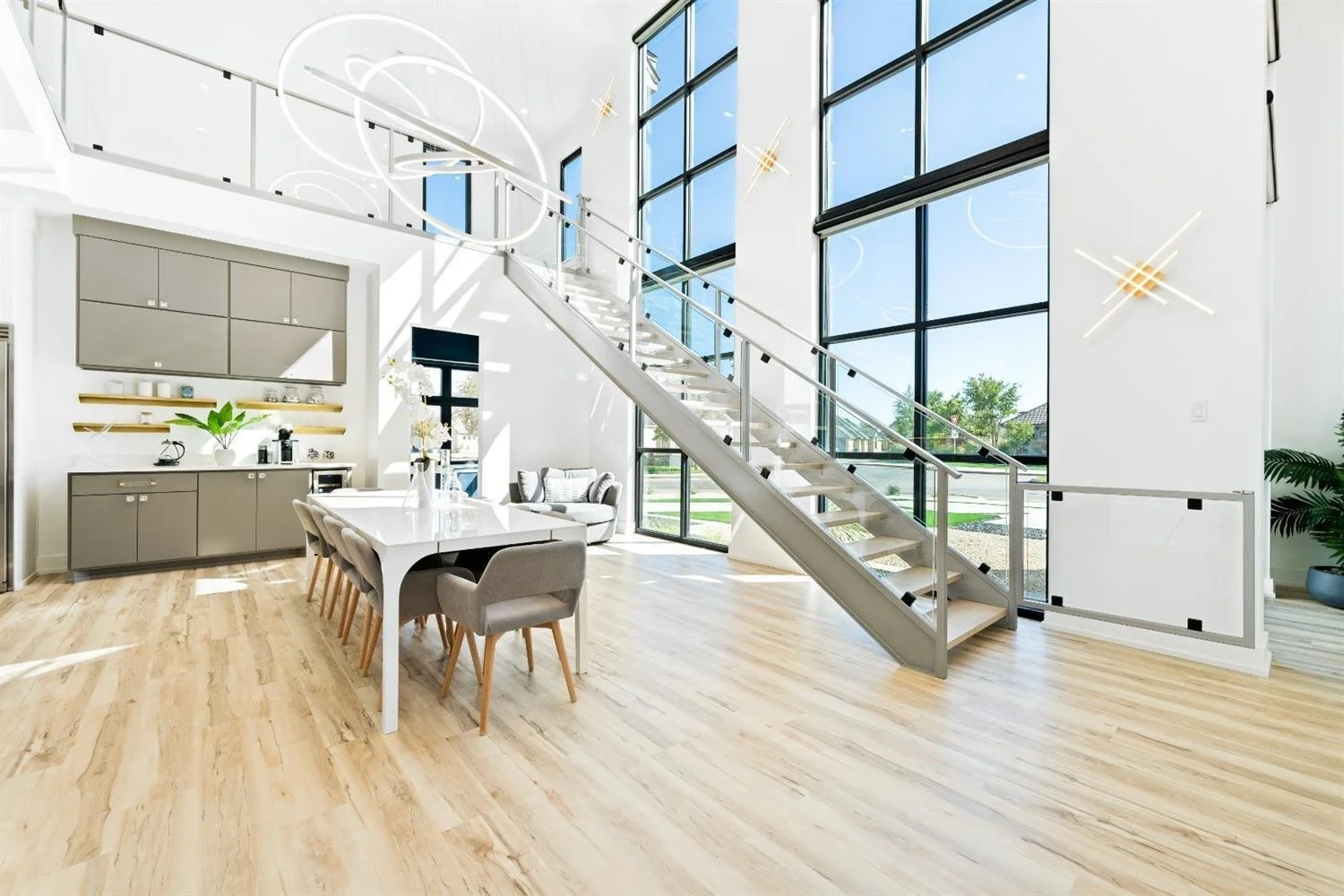 Modern dining area with tall windows and an open staircase.