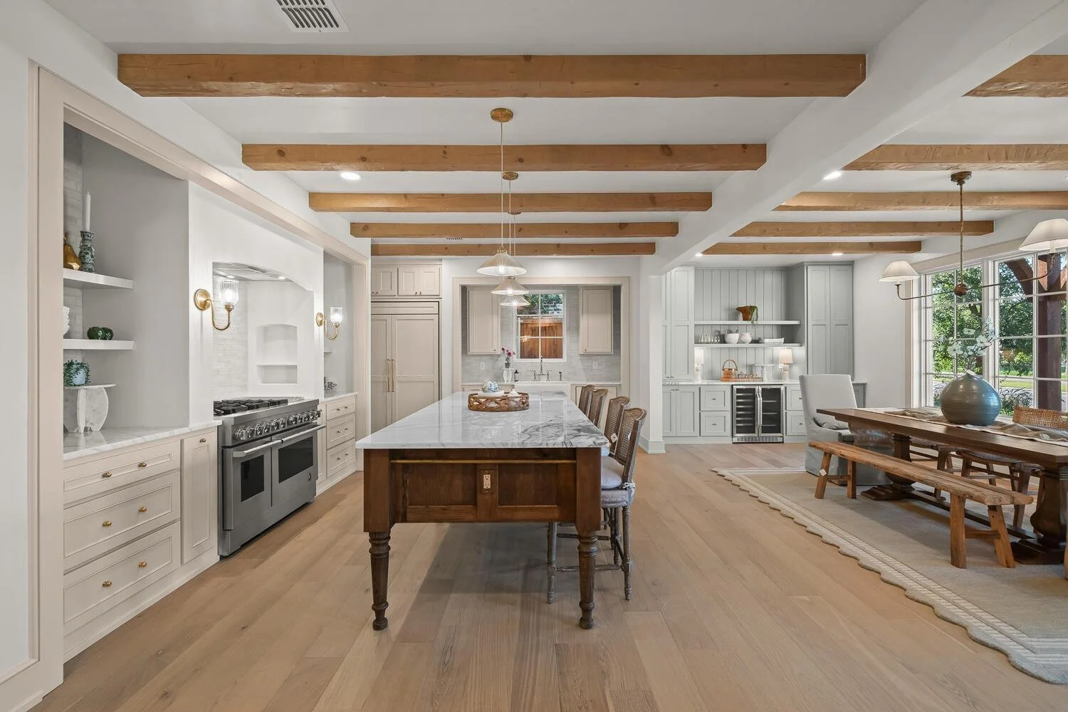 Kitchen and dining area with wood ceiling beams and a large stone-topped island.