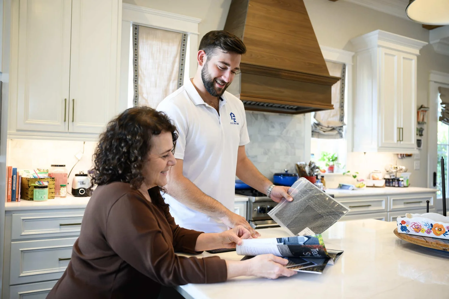 Homeowner and Epic Roofing estimator looking at a shingle sample in a kitchen